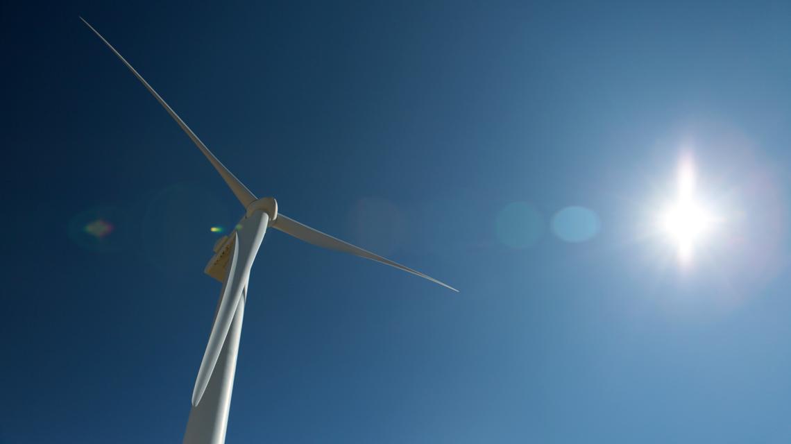 一个白色的风力涡轮机映衬着明亮的蓝天